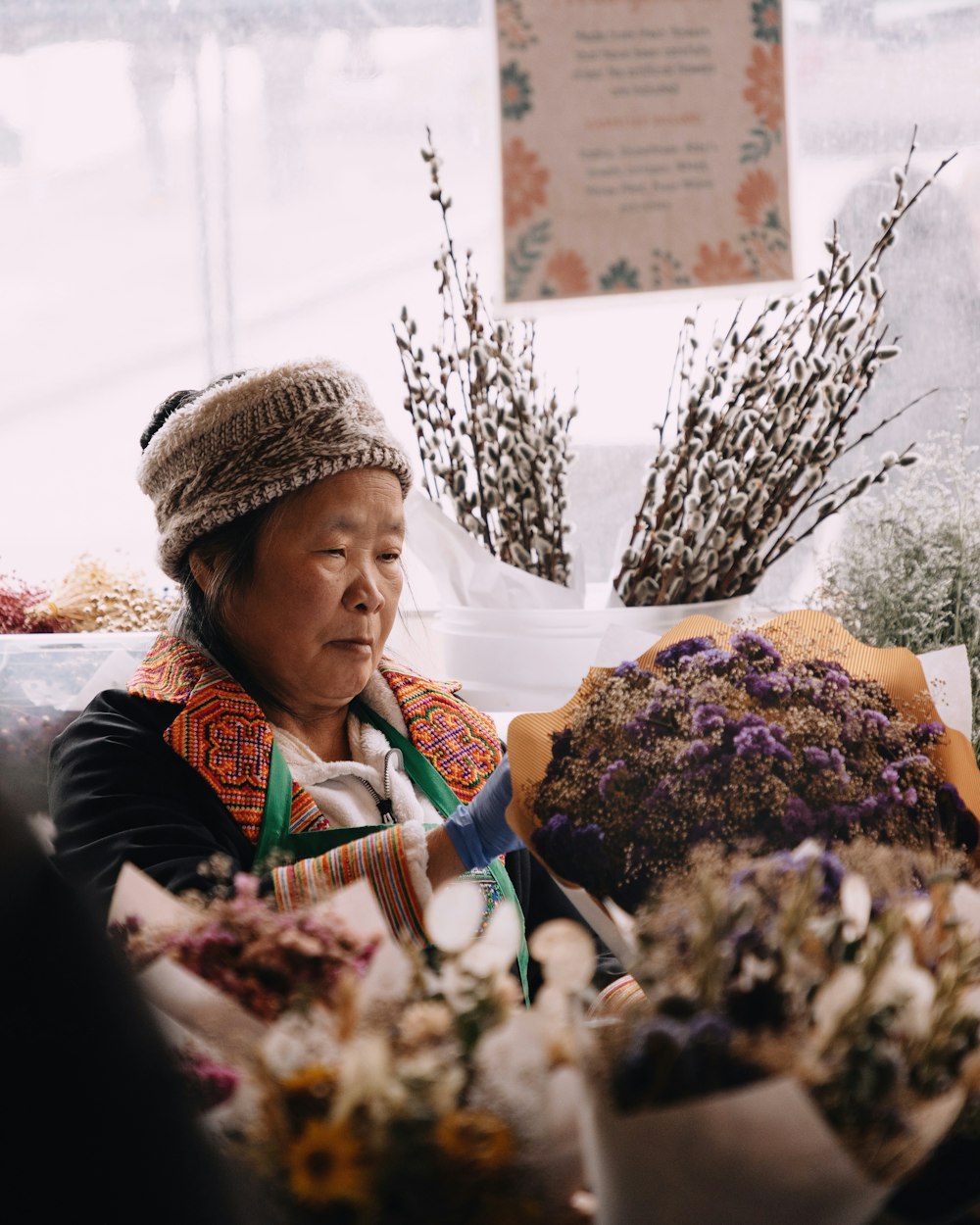 a woman sitting in front of a bunch of flowers