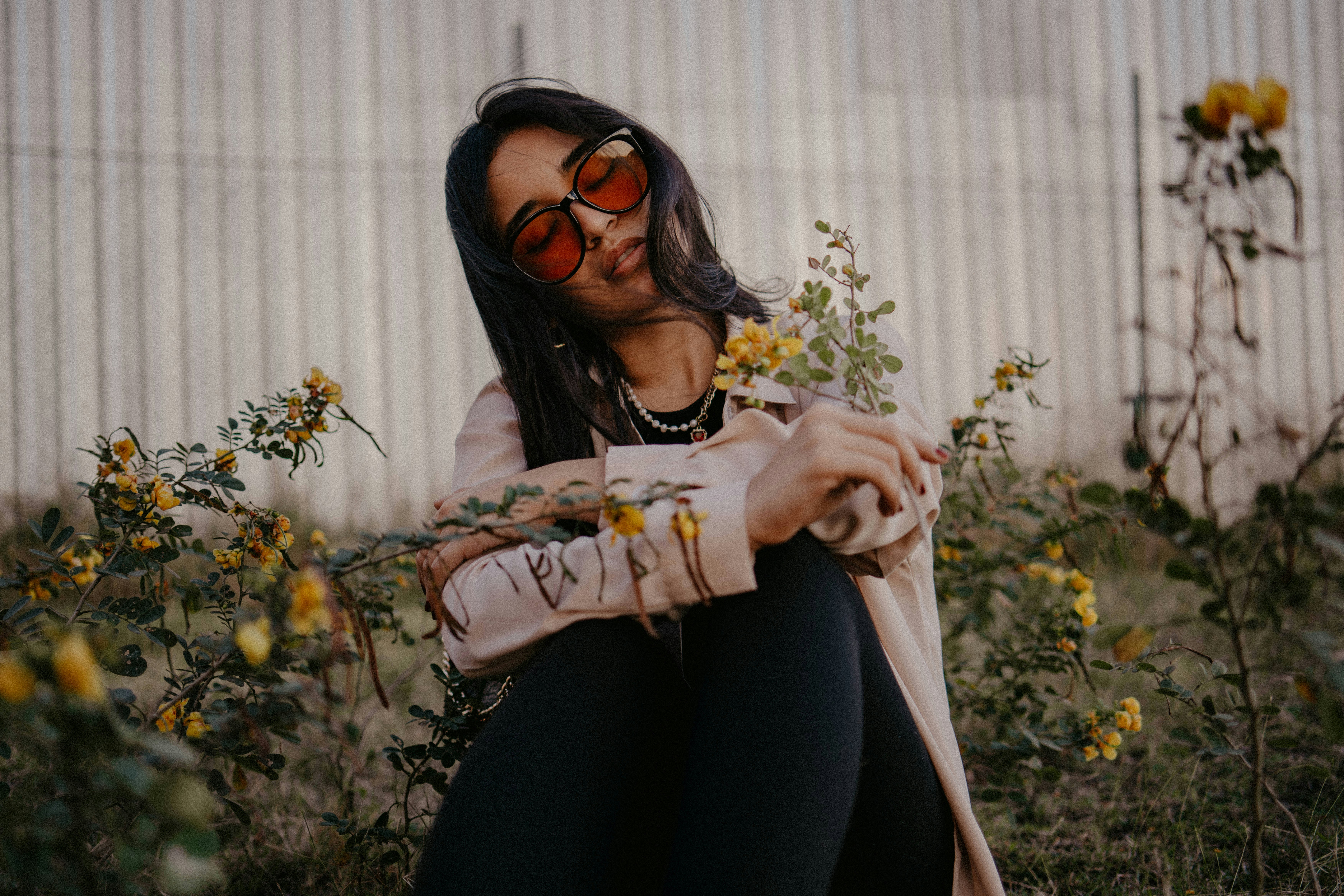 꽃밭에 앉아 선글라스를 쓴 여자