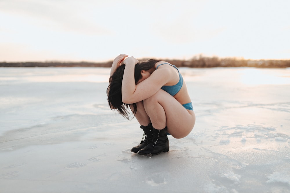 a woman kneeling down on a frozen lake