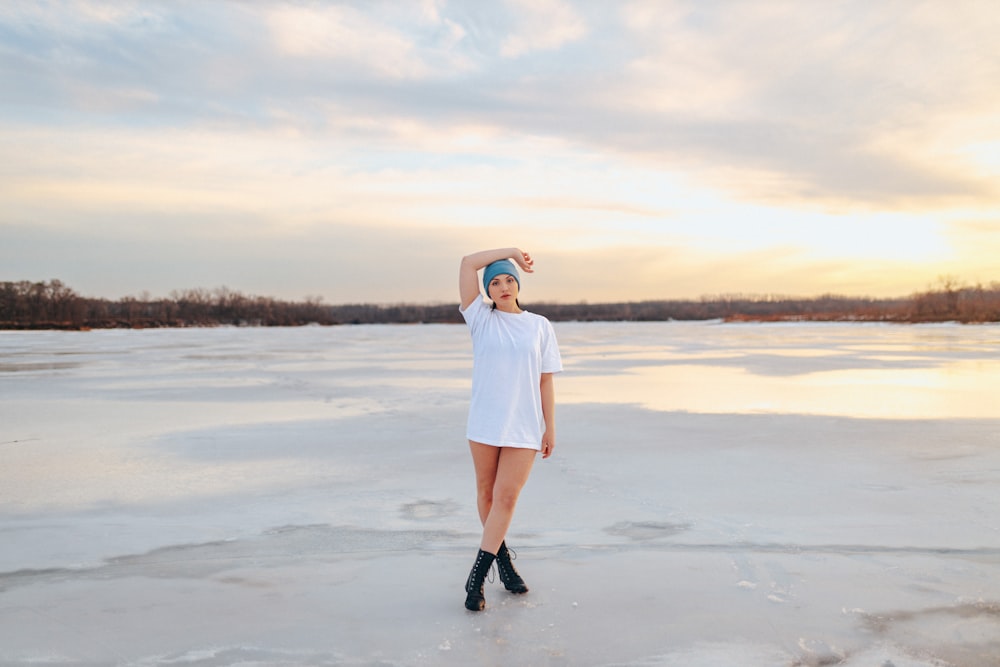 a woman in a white dress standing on a frozen lake