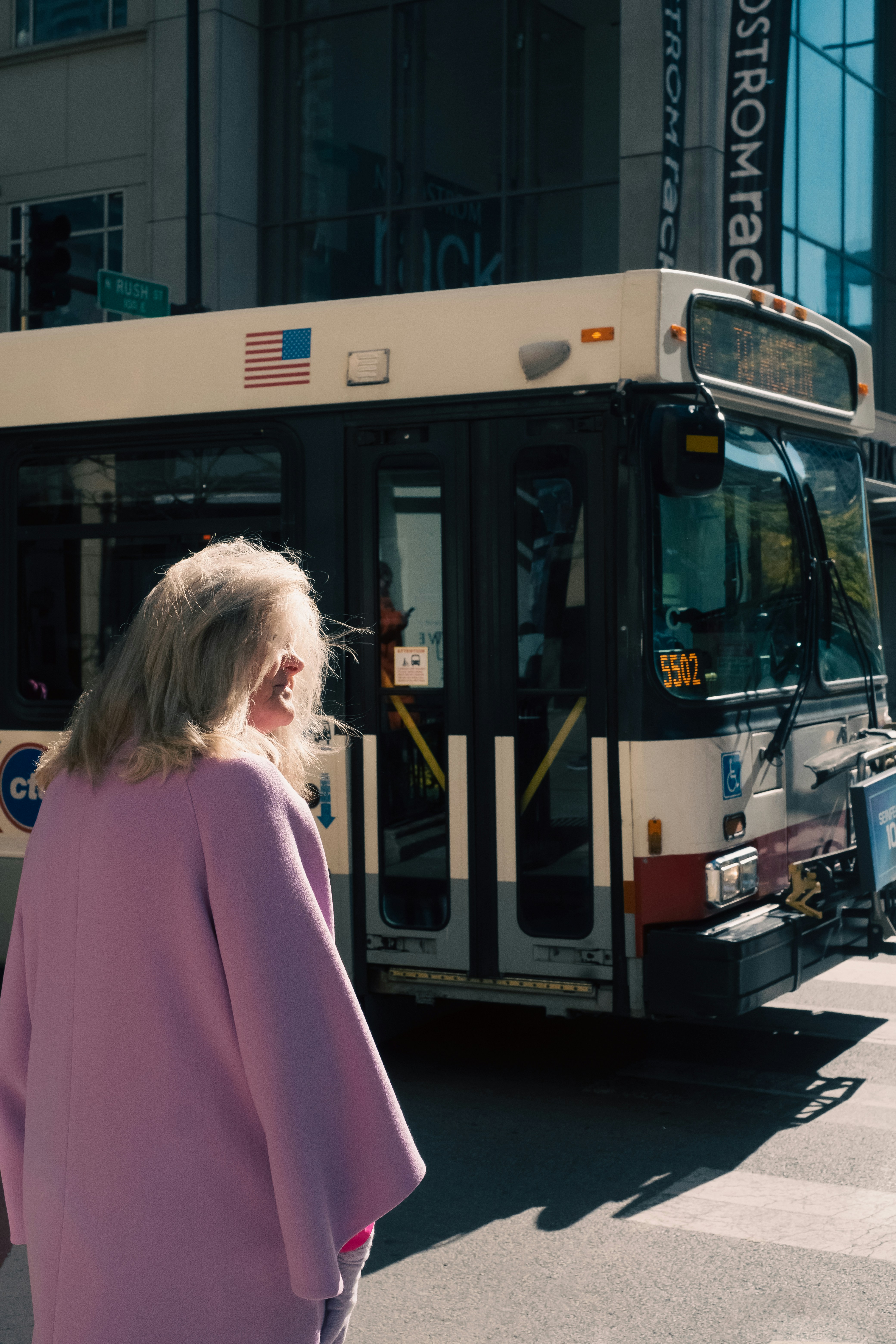 a woman standing in front of a bus on a city street