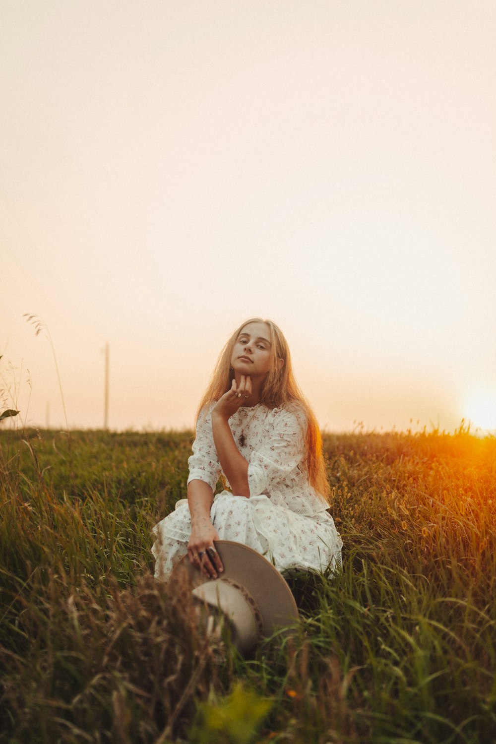 a woman sitting in a field with a hat