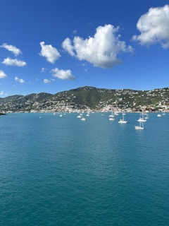 A serene turquoise ocean view with a sailboat gliding near a sunlit tropical beach.