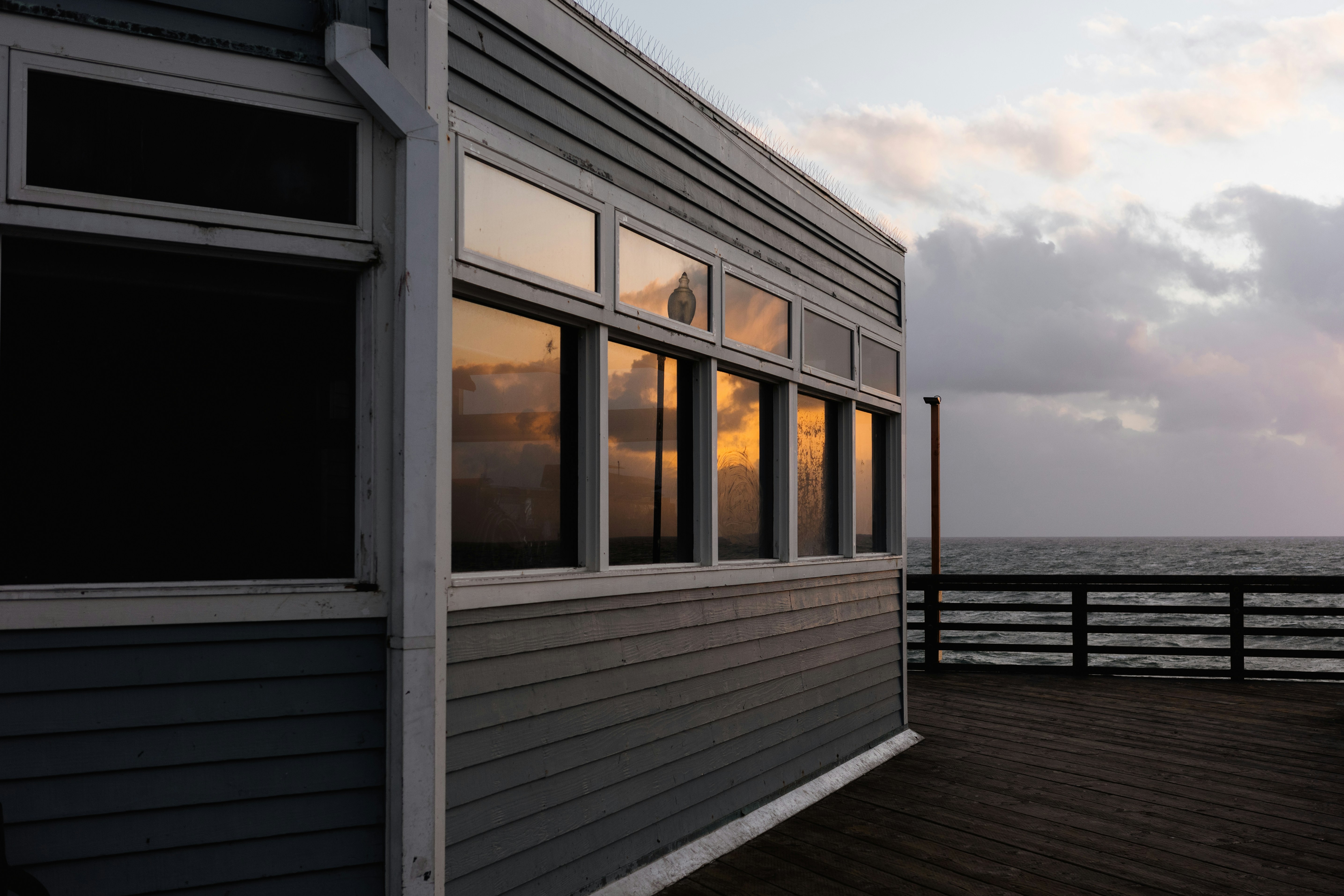 Material comparison showing wood, composite, and PVC decking samples with coastal home backdrop - deck construction Huntington