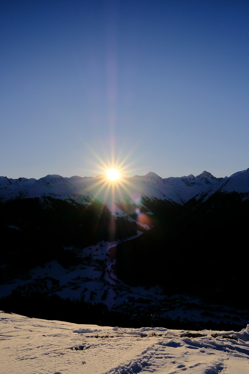 the sun is shining over a snowy mountain