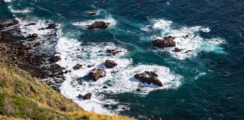 an aerial view of the ocean with rocks in the foreground