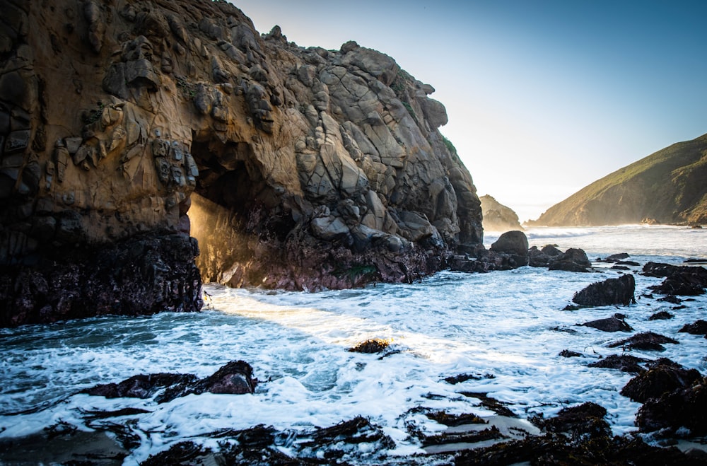 a rocky beach with a cave in the middle of it