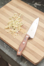 Close-up of a sharp chef’s knife resting on a wooden cutting board.
