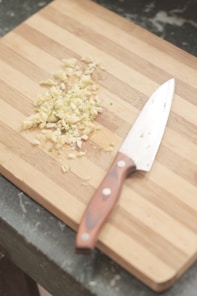 A chopping board with a carved handle resting next to a chef's knife.