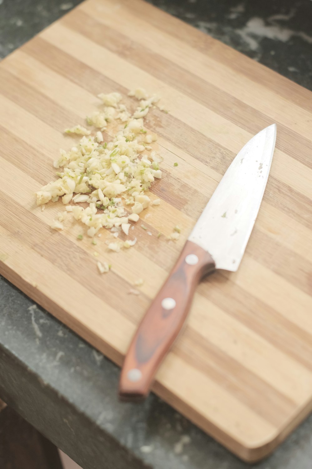 a cutting board with a knife and chopped food on it