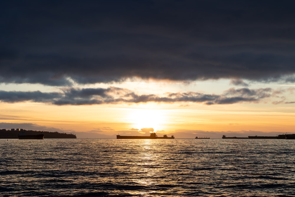 a sunset over a body of water with ships in the distance