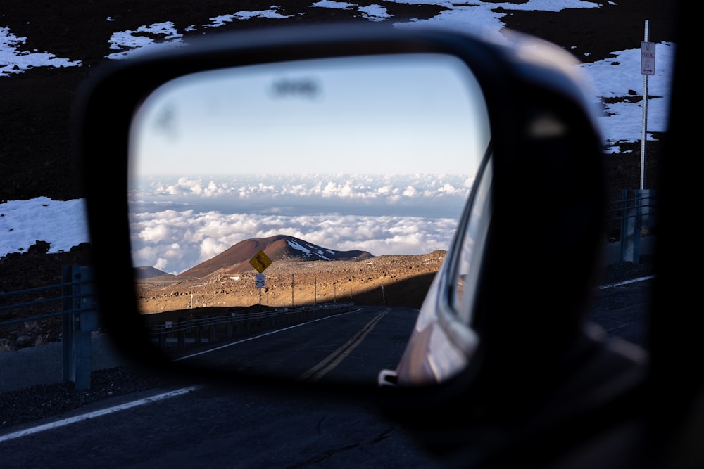a rear view mirror on a car with a mountain in the background