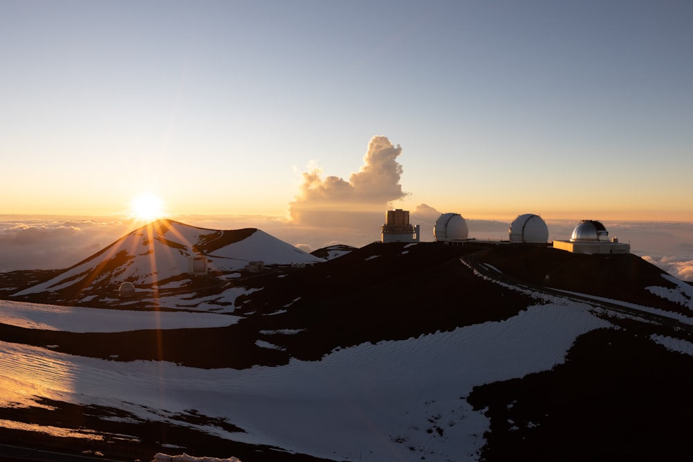 the sun is setting over a snowy mountain