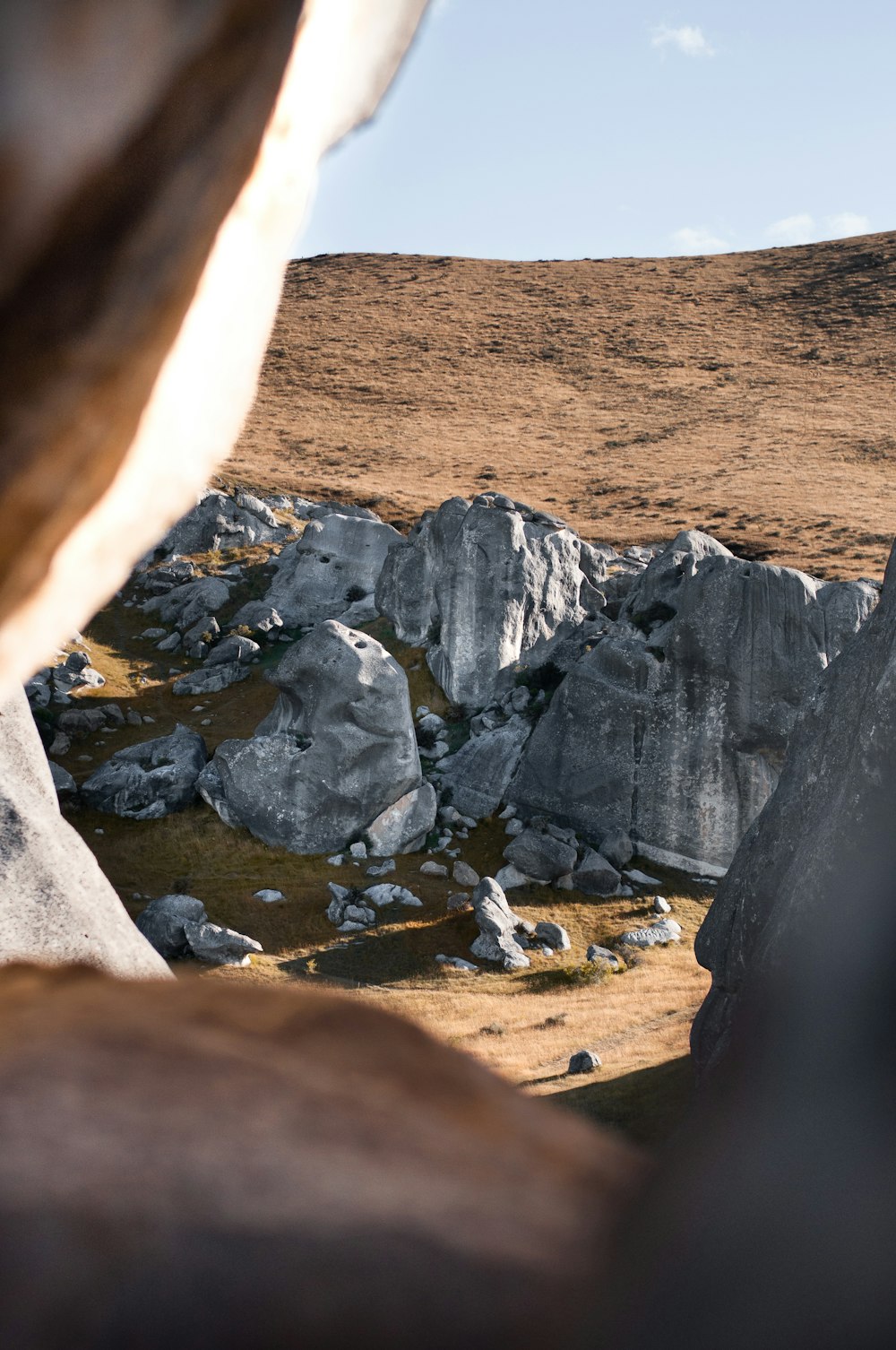 a person standing on a rocky hillside with a mountain in the background