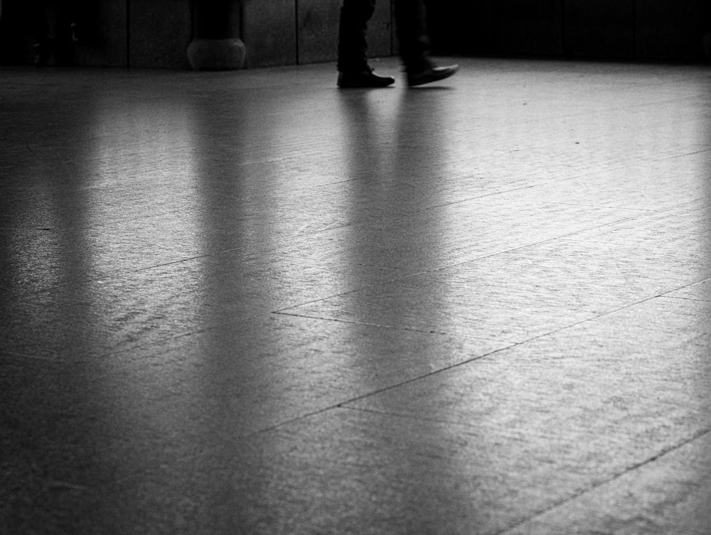 a black and white photo of a person standing on a tile floor