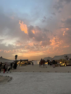 Group of travelers enjoying a sunset dinner in the Sahara desert camp.