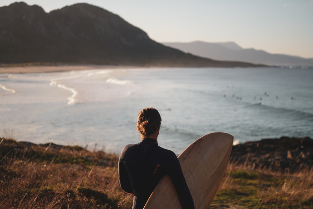 a man holding a surfboard looking out at the ocean