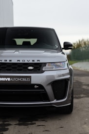 A sleek and modern Land Rover vehicle is parked on a paved surface, displayed prominently with its front facing the camera. The body is sleek with a metallic finish, and the grille and headlights convey a sense of luxury and robustness.