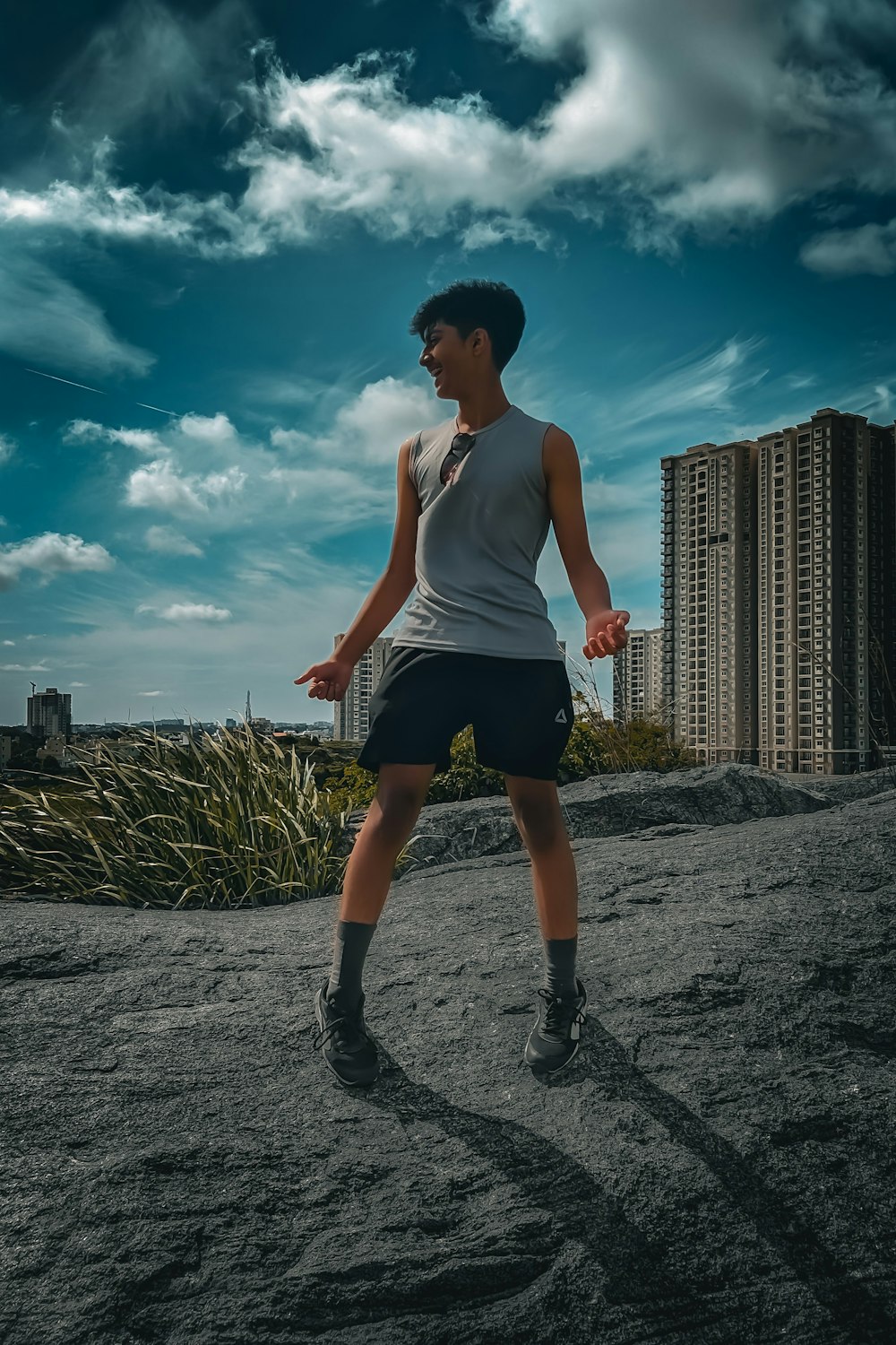 a man standing on top of a rock near tall buildings