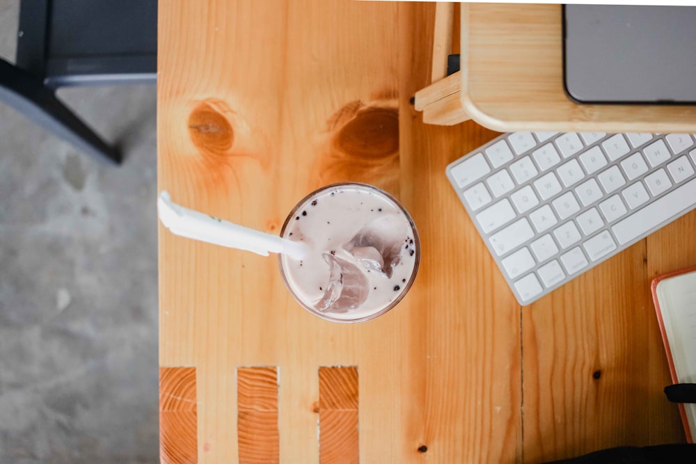 a computer desk with a keyboard and a drink