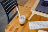 A compact, portable cooler sitting on a wooden desk beside a laptop.