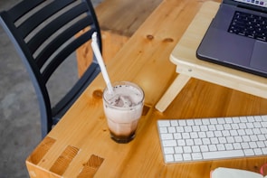 A compact, portable cooler sitting on a wooden desk beside a laptop.