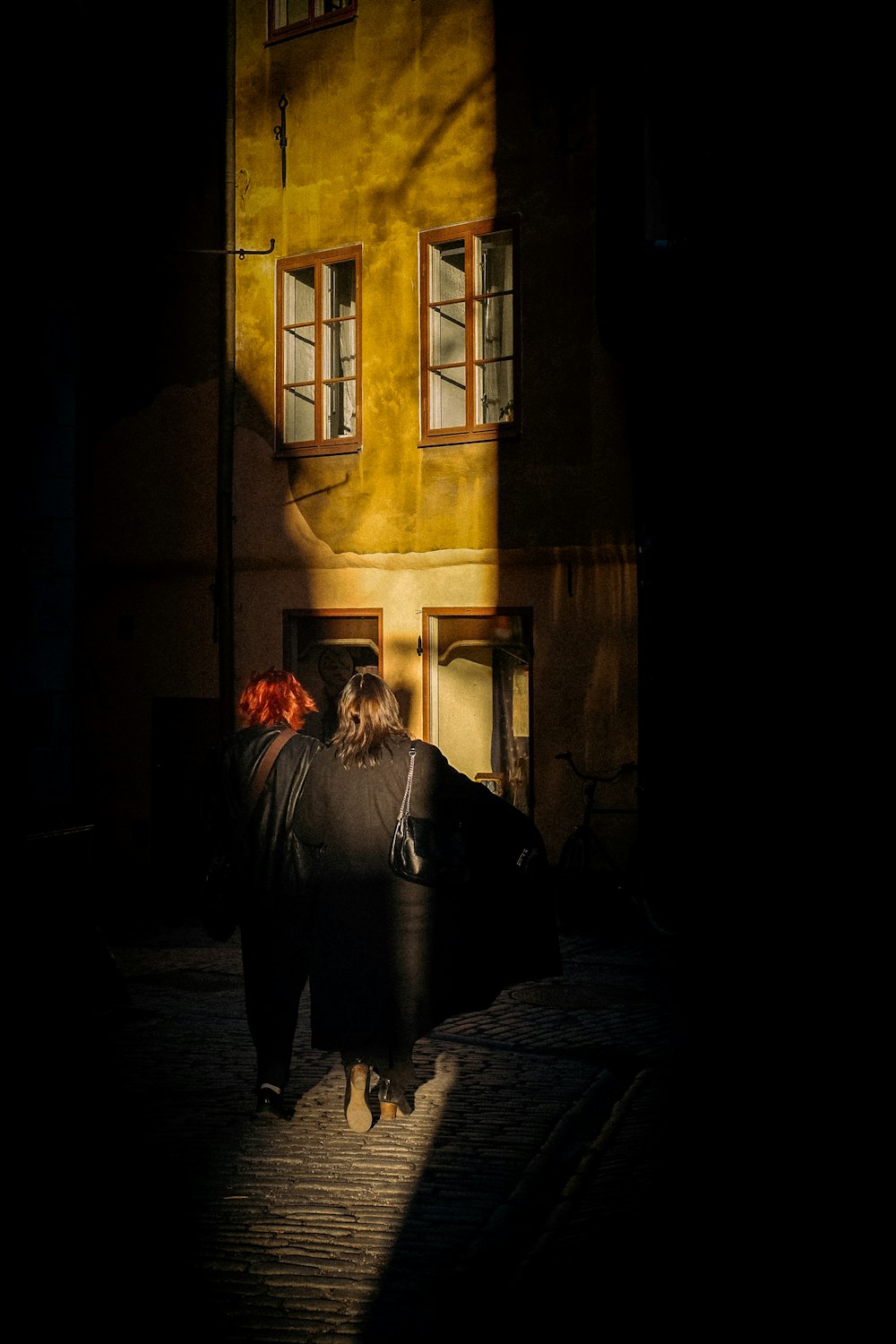 a woman walking down a street next to a tall building