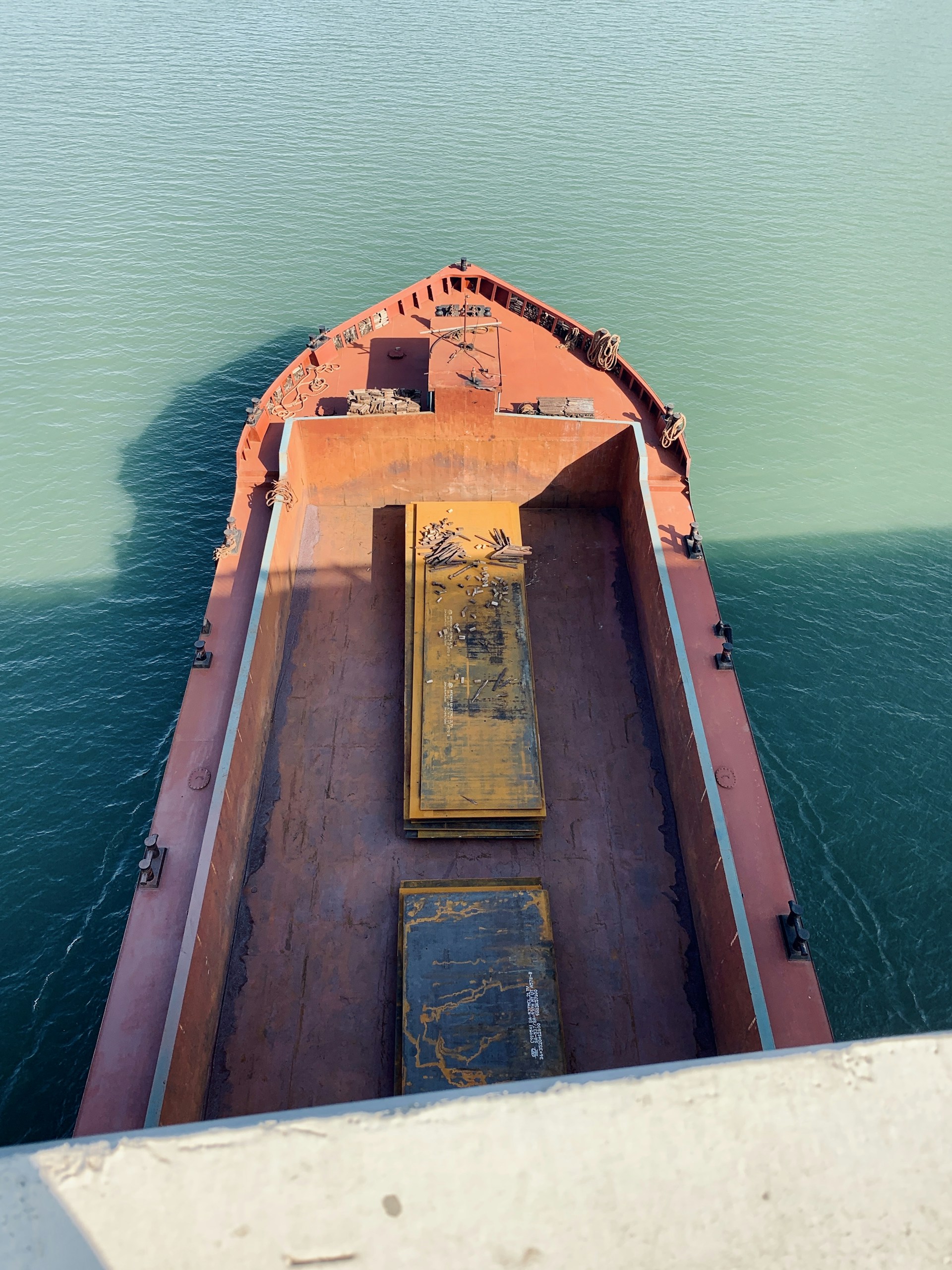 A detailed close-up of a marine surveyor inspecting the hull of a cargo ship under bright daylight.