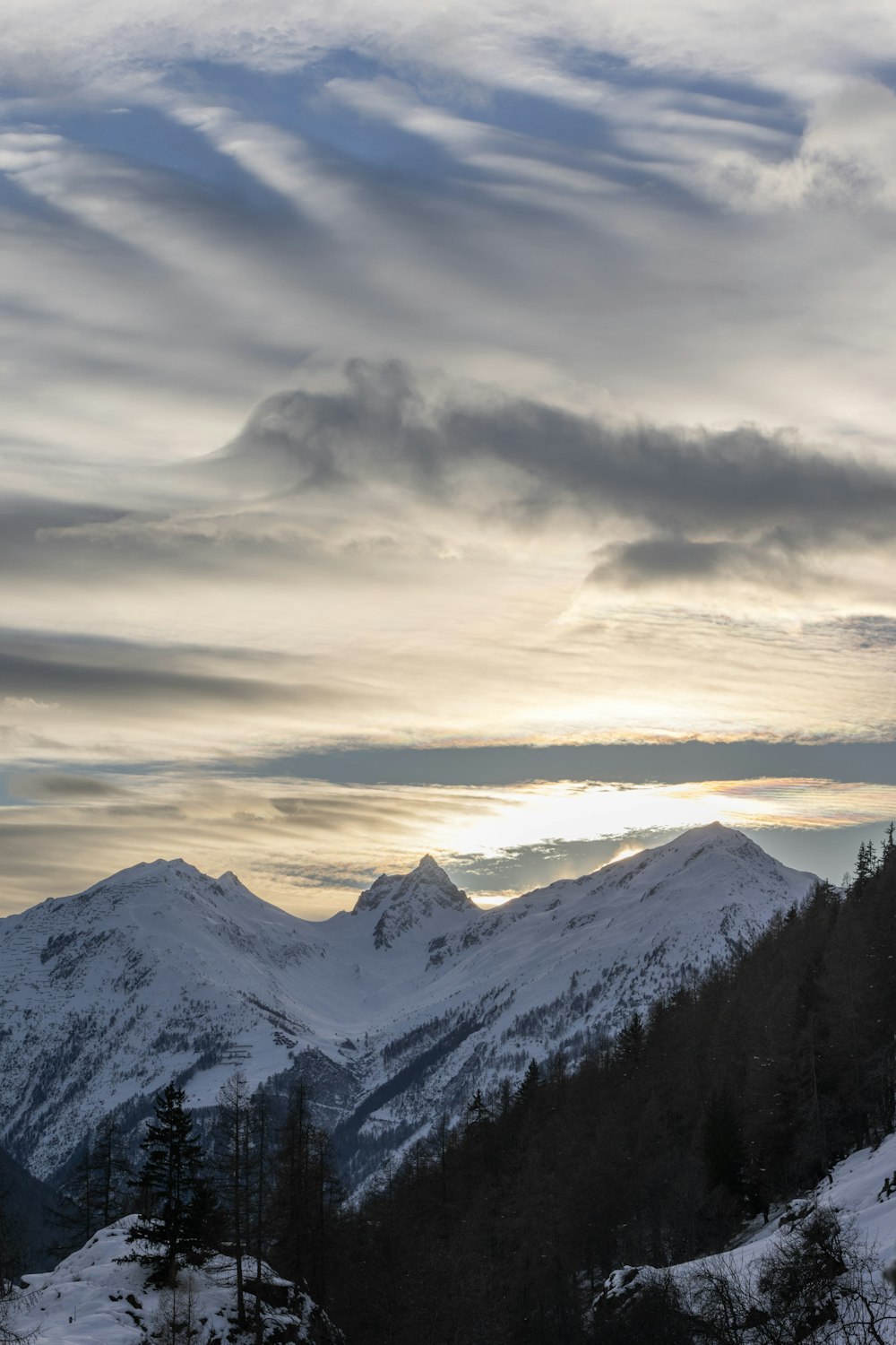 the sun is setting over the snowy mountains