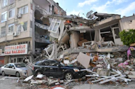 a car is parked in front of a destroyed building