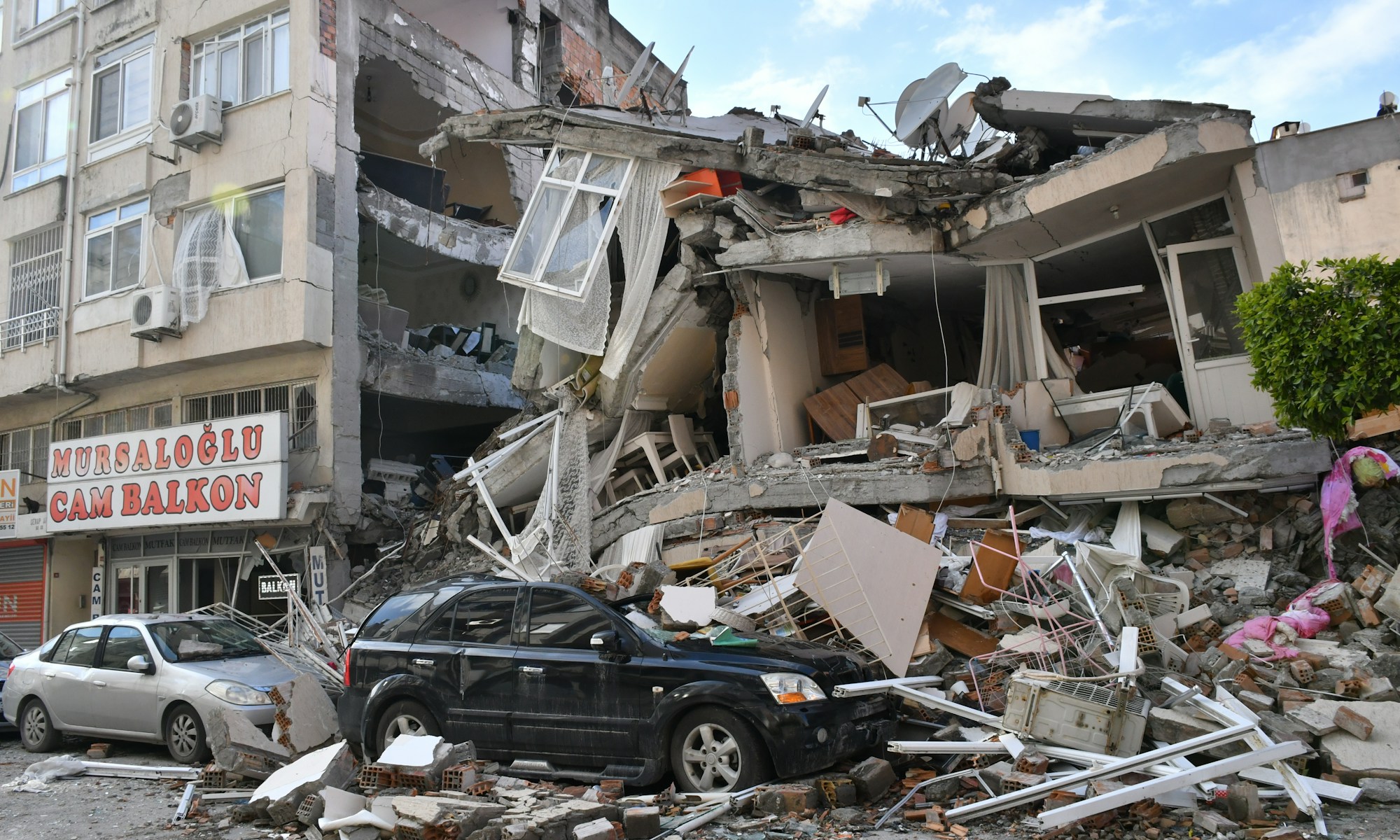 a car is parked in front of a destroyed building