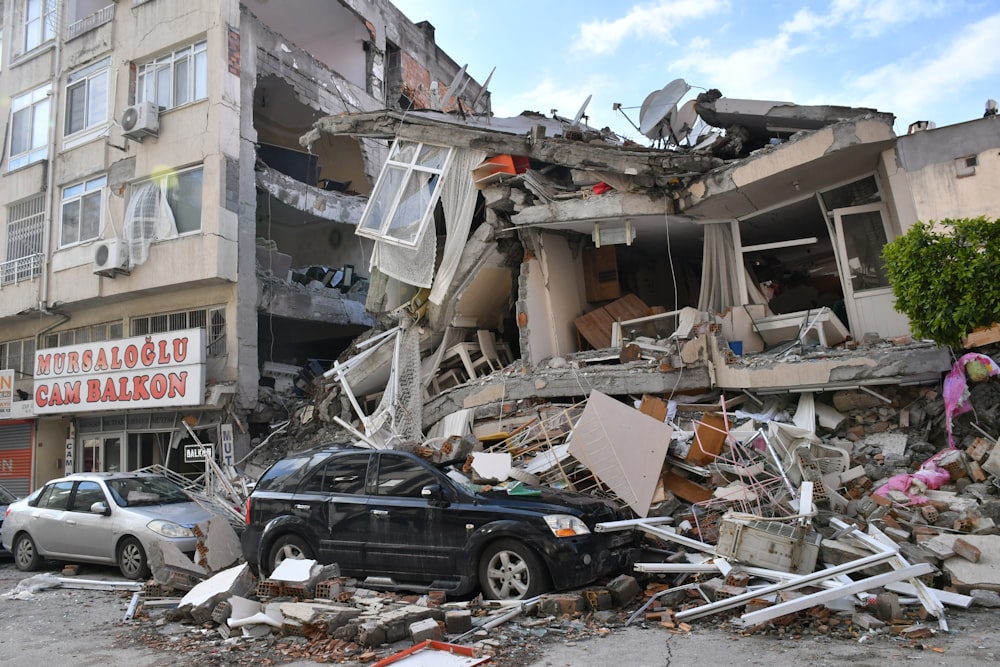 破壊された建物の前に車が駐車されている