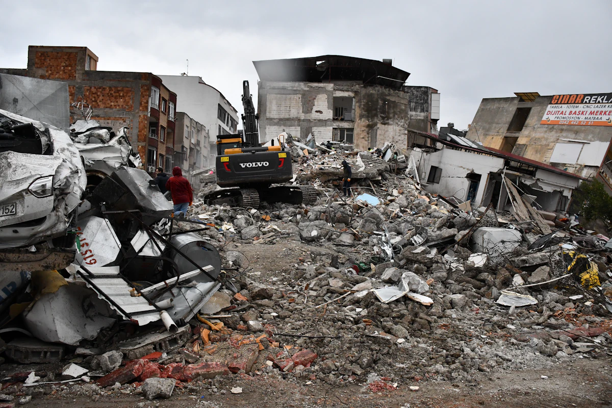 Collapsed building rubble after a major earthquake — rescue workers and heavy equipment work through debris