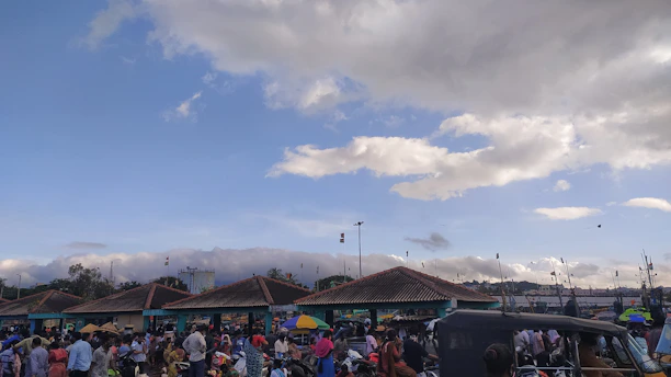 A vibrant street market in Touros with colorful stalls and happy visitors under a bright blue sky.