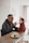 A smiling father feeding his baby with a baby spoon in a bright kitchen.