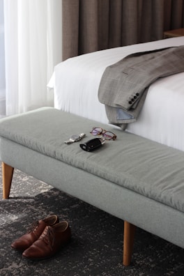 A stylish outfit laid out on a bed, including a jacket, shirt, and pants.