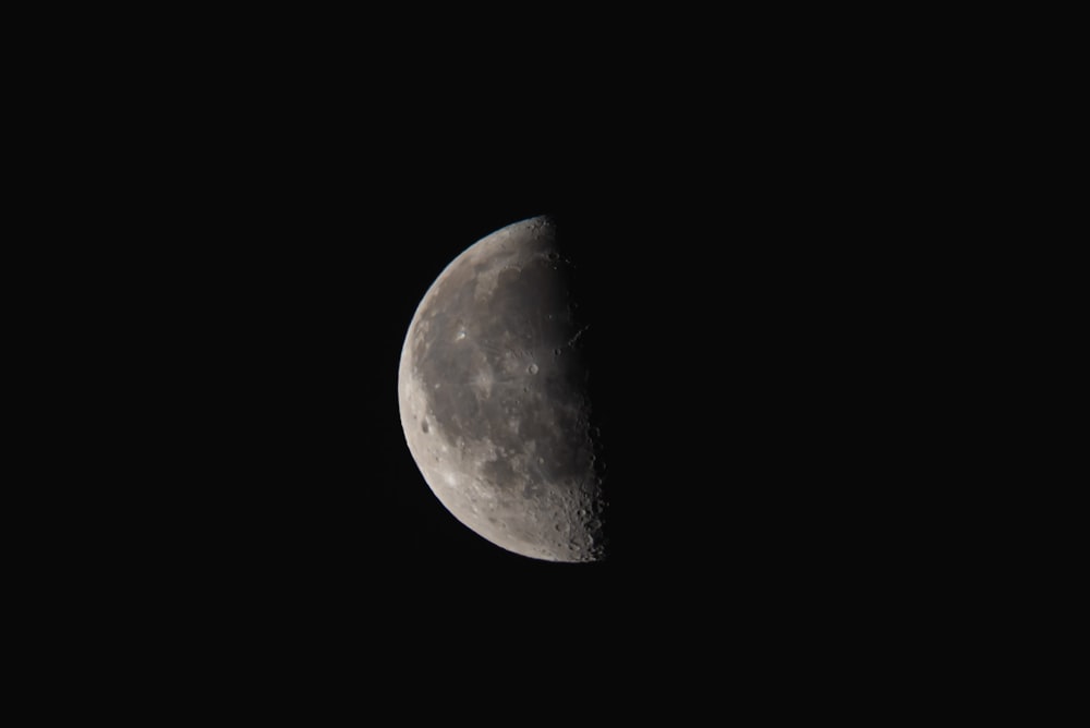 a half moon is seen in the dark sky