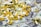 A collection of various pills and capsules, including yellow, white, and transparent ones, is scattered over a background of hundred-dollar bills.