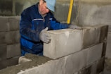 Worker wearing a helmet checking the alignment of bricks with a level.