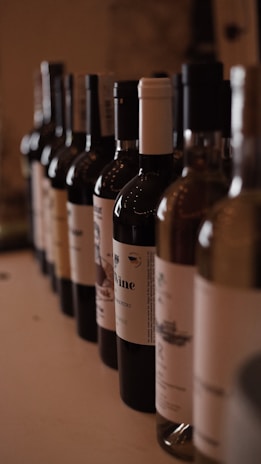 Rows of wine bottles with elegant labels illuminated by warm lighting.