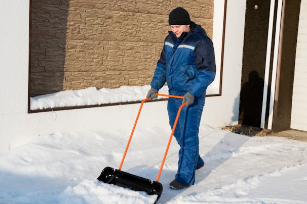 Staff member shoveling a narrow path beside a home, ensuring safe access.