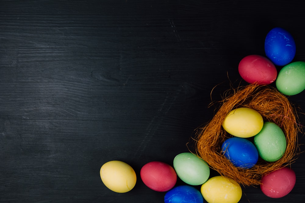 a bunch of colored eggs sitting in a nest