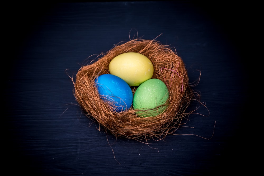 three eggs in a nest on a black background