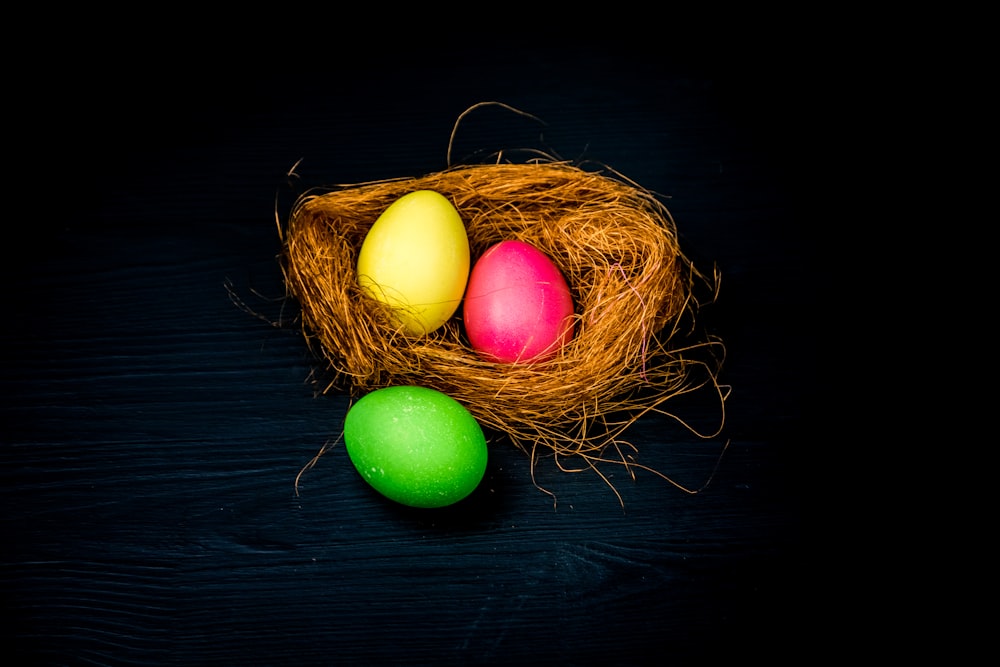 three colored eggs in a nest on a black background