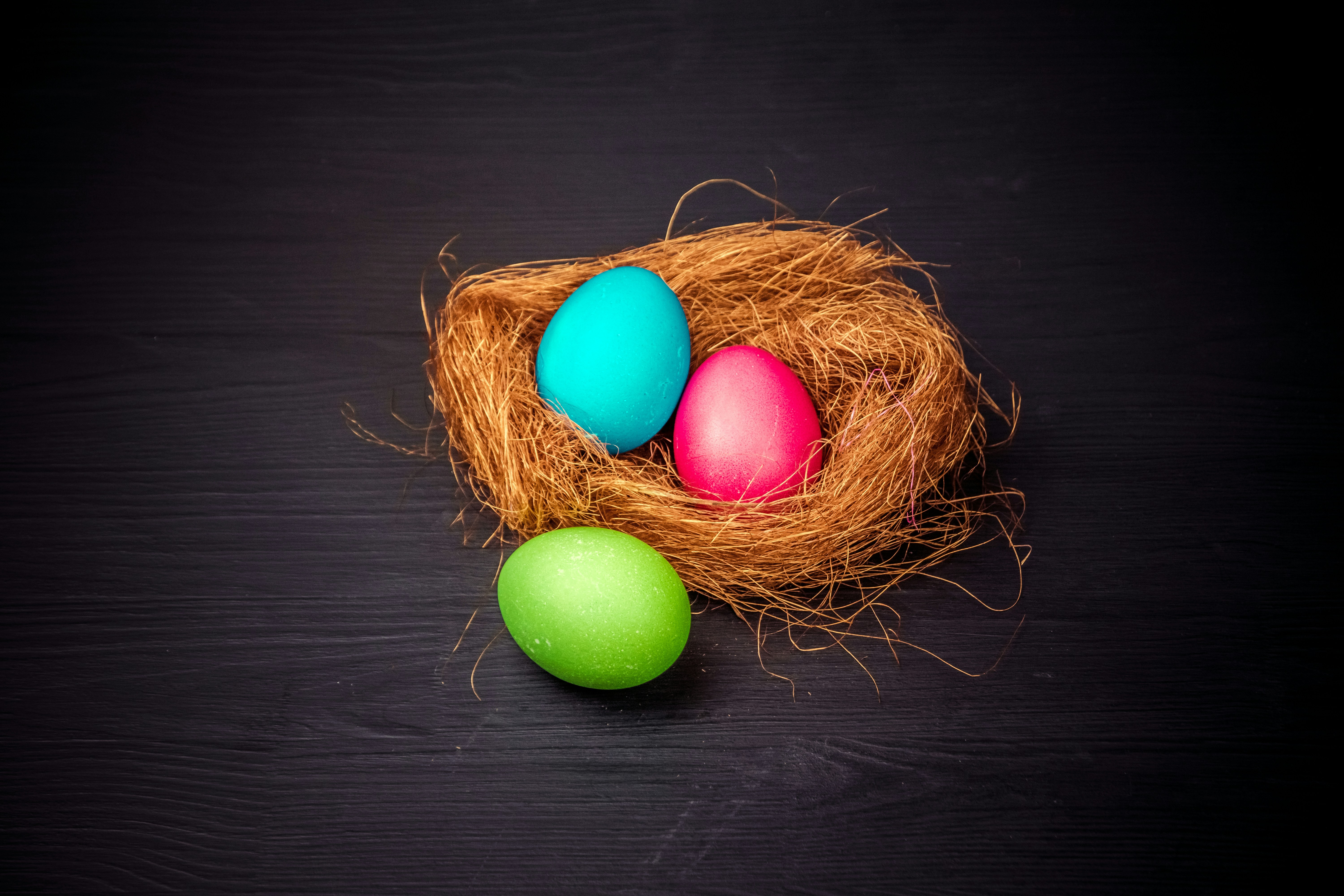 three colored eggs in a nest on a black background