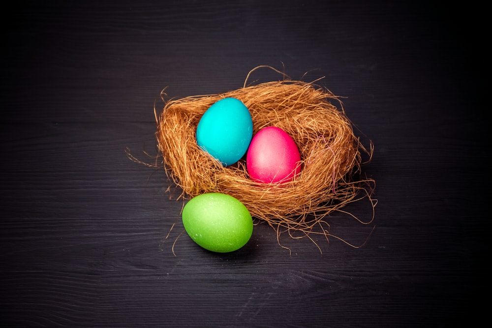 three colored eggs in a nest on a black background