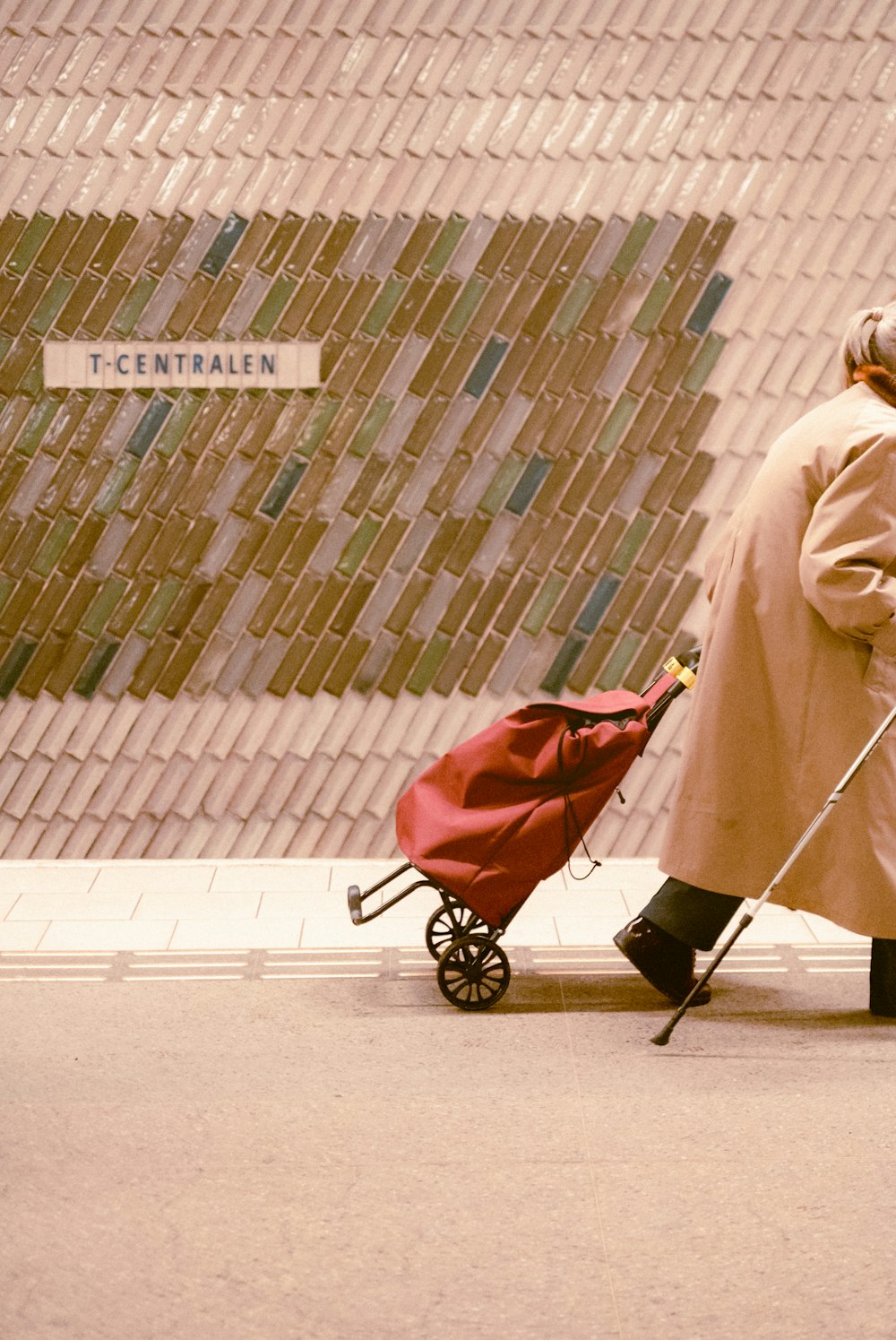 a man in a trench coat pulling a red cart