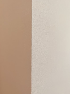 Close-up of a freshly painted living room wall in soft beige with crisp white trim.