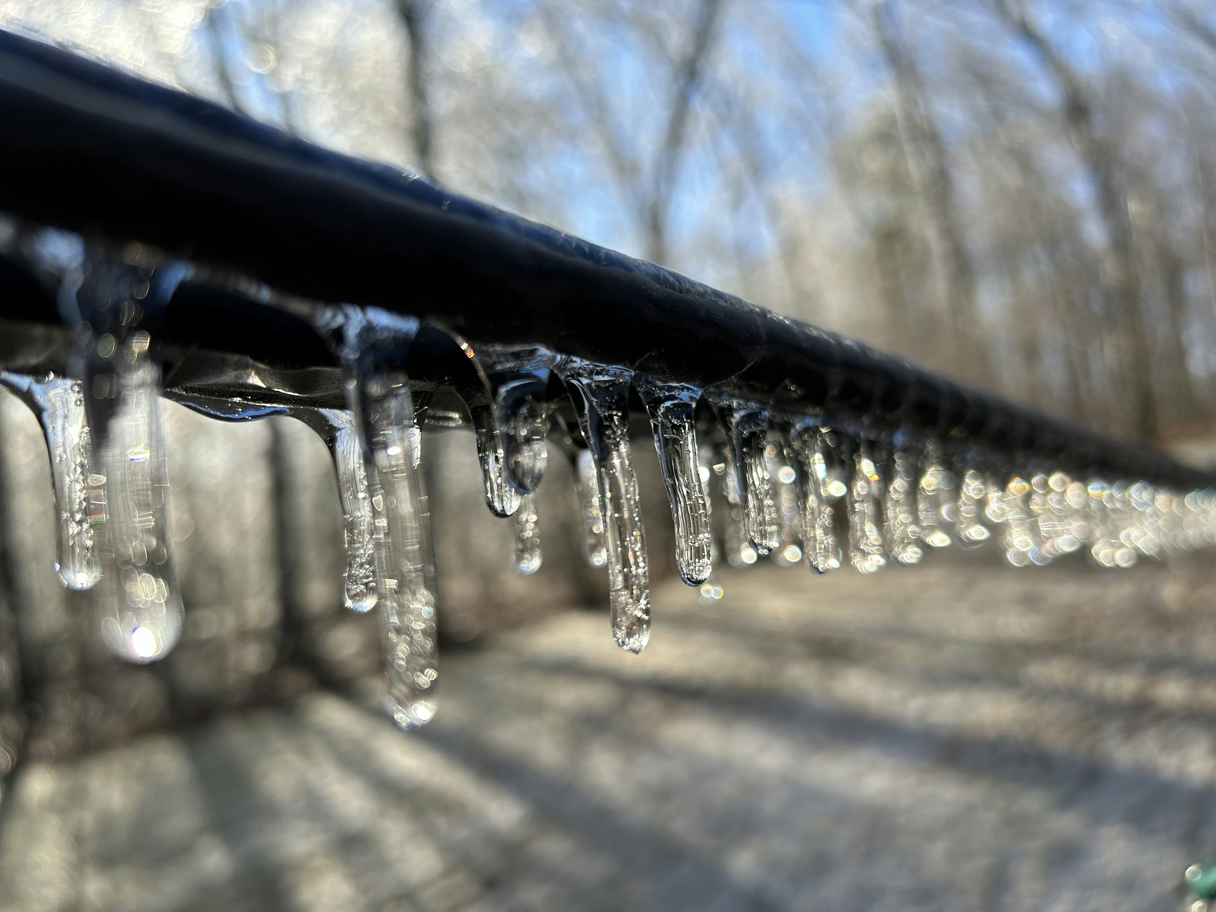a line of water droplets hanging from a metal rail