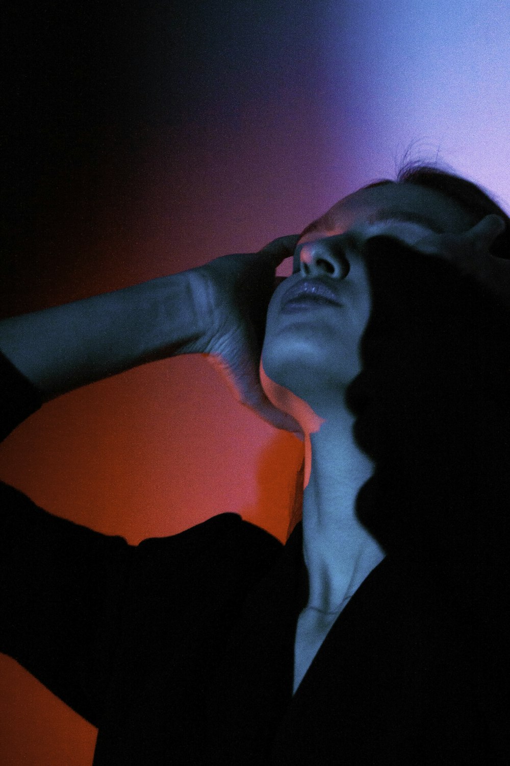 a woman standing in a dark room with her hand on her head